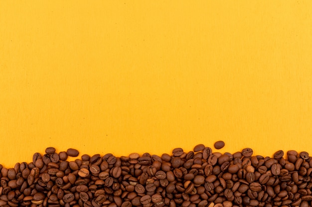 Kaffeebohnen mit Kopienraum auf gelber Oberfläche