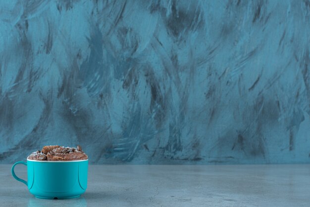 Kaffeebohnen und Maispads in einer Tasse auf blauem Hintergrund.