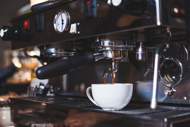 Kaffeemaschine gießt frisch Kaffee in der weißen Schale