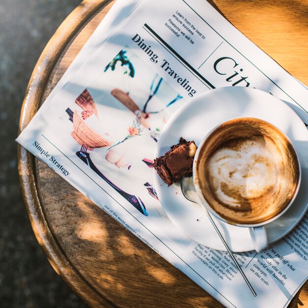 Kaffeestube-Café Latte Cappuccino-Zeitungs-Schokoladenkuchen-Konzept