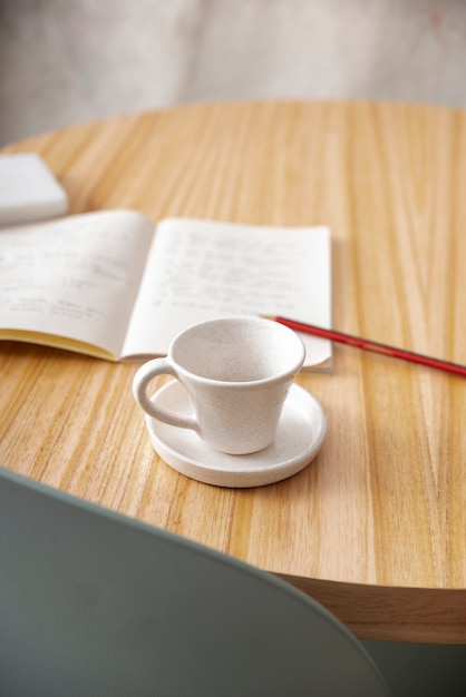 Kaffeetasse des hohen Winkels auf Notizbuchanordnung