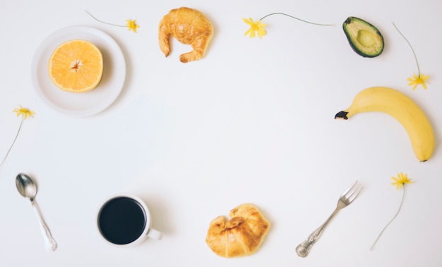 Kaffeetasse; halbierte Orange; Croissants; Avocado; Banane; Croissants und Kaffeetasse mit Textfreiraum für Text