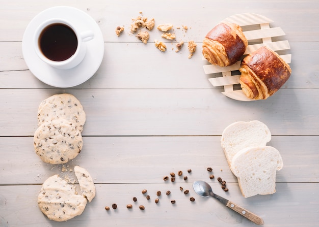 Kaffeetasse mit Brötchen und Keksen auf Tabelle