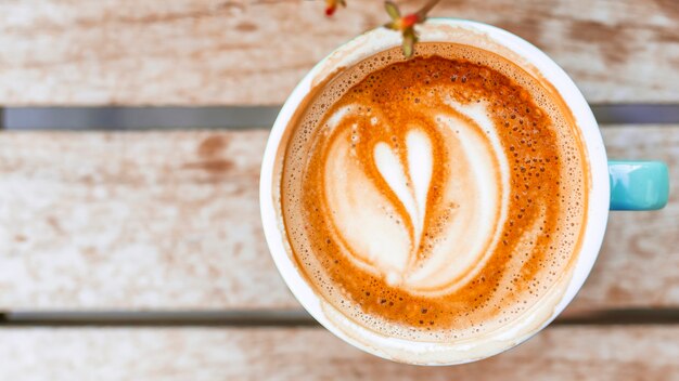 Kaffeetasse mit Herzform Lattekunst auf hölzerner Tabelle