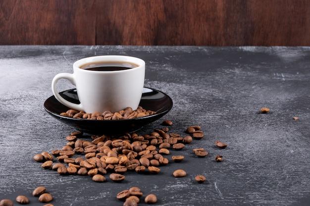 Kaffeetasse mit Kaffeebohnen auf dunkler Tabelle