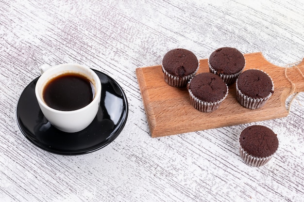 Kaffeetasse mit Schokoladenmuffins auf hölzernem Brett