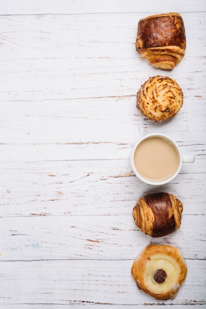 Kostenloses Foto kaffeetasse mit süßen brötchen auf leuchtpult