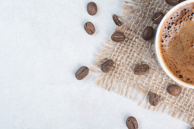 Kaffeetasse und Kaffeebohnen auf Sackleinen. Hochwertiges Foto