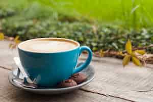 Kostenloses Foto kaffeetasse und plätzchen auf holzoberfläche mit defocus grünnaturhintergrund