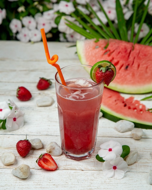 Kalte Wassermelonenerdbeerkuice mit Eiswürfeln und Früchten herum.