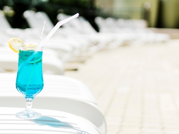 Kaltes blaues Cocktail mit Zitrone auf Sonnenruhesessel