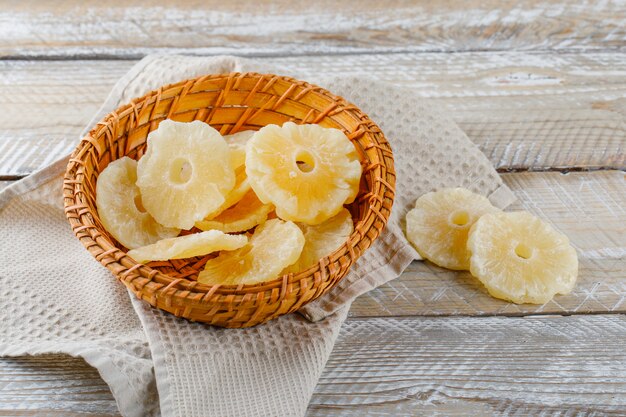 Kandierte Ananas in einem Korb auf Holz- und Küchentuchoberfläche