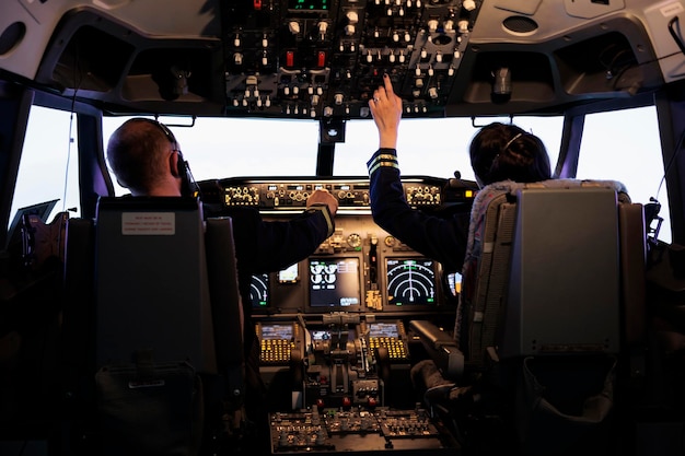 Kapitän und Copilotin machen sich bereit, Flugzeug und Start mit Dashboard-Navigation im Cockpit-Befehl zu fliegen. Airline-Crew zur Festlegung der Höhe und mit Bedienfeldtasten, fliegendes Flugzeug.