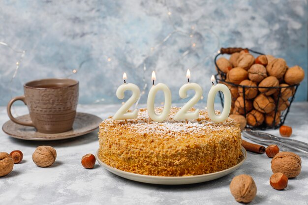 Karottenkuchen mit 2020 Kerzen und einer Tasse Tee auf grauem Beton