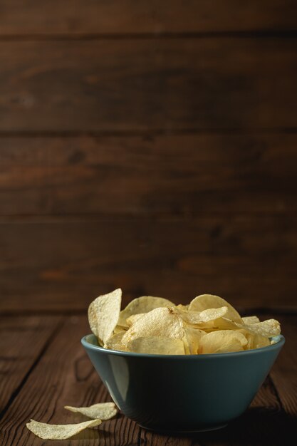 Kartoffelchips in der Schüssel auf einem Holztisch.