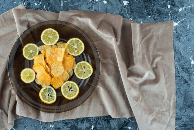 Kartoffelchips in einer Glasplatte auf einem Stoffstück, auf dem Marmortisch.