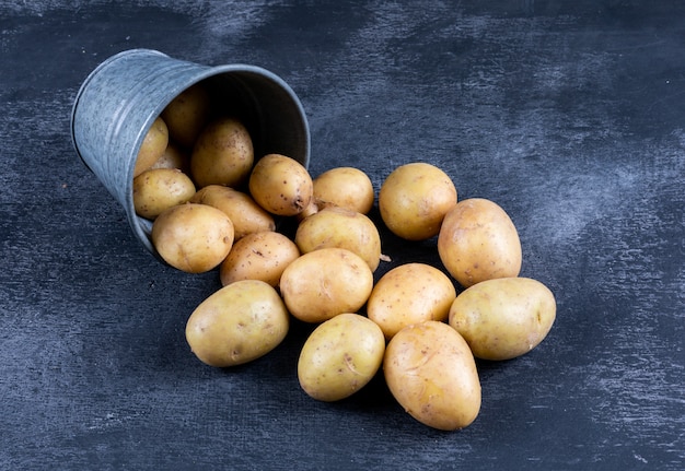 Kartoffeln in einer Eimer-Hochwinkelansicht auf einem dunklen Tisch