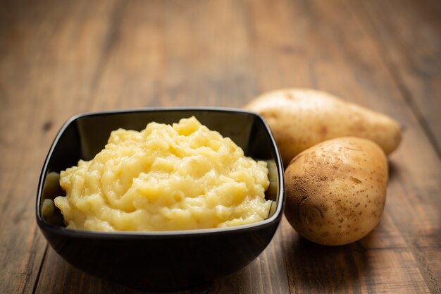 Kartoffelpürees in der Schüssel auf dem weißen Holztisch