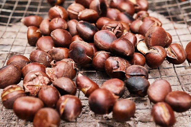 Kastanien werden auf einem Grill über heißem Sand geröstet Saisonale Speisen köstliche Kastanien für Wein Herbsternte selektiver Fokus auf Nüsse