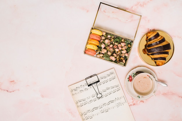 Kasten mit den Blumenknospen und -plätzchen nähern sich Kaffeetasse auf Tabelle