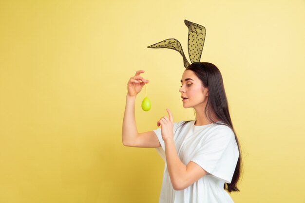 Kaukasische Frau als Osterhase auf gelbem Studiohintergrund.