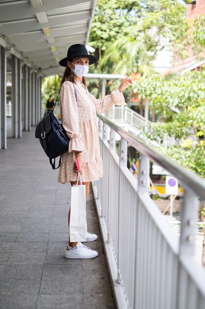 Kaukasische Frau, die auf U-Bahn-Kreuzung in der medizinischen Gesichtsmaske während der Pandämie in der Stadt Bangkok geht.