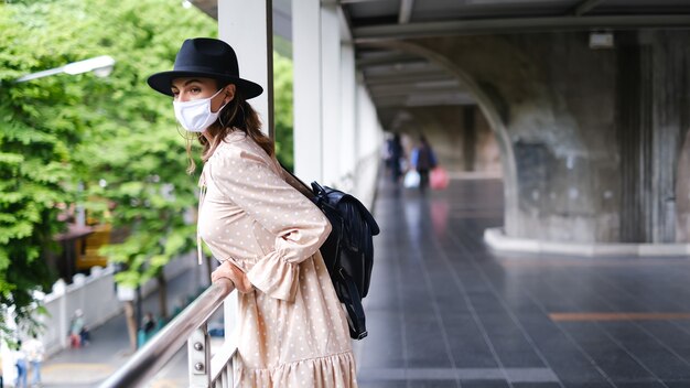 Kaukasische Frau, die auf U-Bahn-Kreuzung in der medizinischen Gesichtsmaske während der Pandämie in der Stadt Bangkok geht.