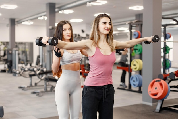 Kaukasische Frau, die Übungen im Fitnessstudio mit persönlicher Trainerin macht