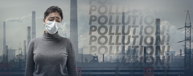 Kaukasische Frau mit Atemschutzmaske gegen Luftverschmutzung, Staubpartikel überschreiten die Sicherheitsgrenzen wegen rauchender Fabriken.