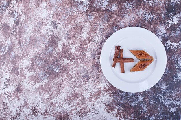 Kaukasische Pakhlava mit Zimtstangen in einem weißen Teller. Hochwertiges Foto