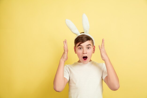 Kaukasischer Junge als Osterhase auf gelbem Hintergrund. Fröhliche Ostergrüße. Schönes männliches Modell.