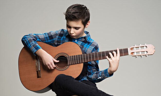 Kaukasischer Junge, der auf akustischer Gitarre spielt.