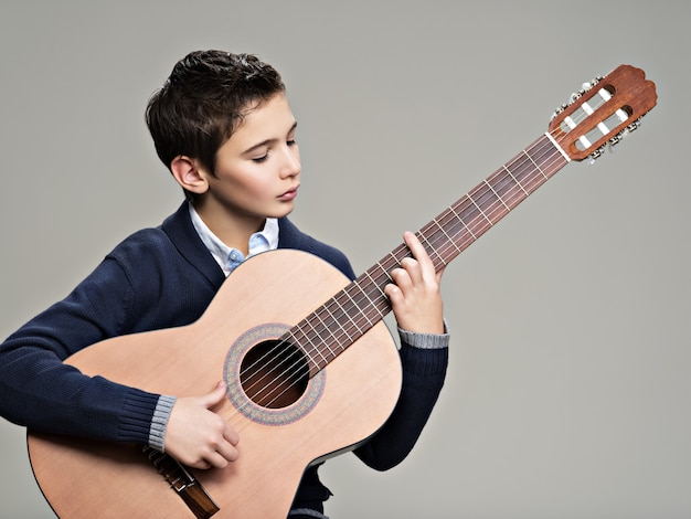 Kaukasischer Junge, der auf akustischer Gitarre spielt.