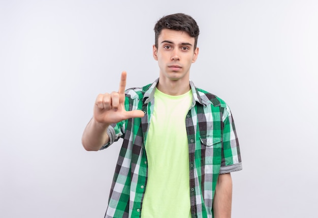 kaukasischer junger Mann, der grünes Hemd trägt, das Geste auf isolierter weißer Wand zeigt