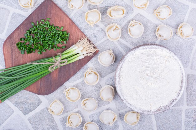 Kaukasischer Khinkali-Teig auf einem Holzbrett mit Frühlingszwiebeln