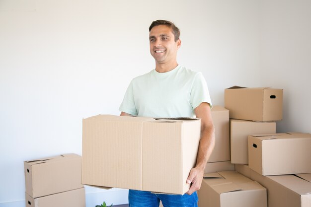 Kaukasischer Mann, der Karton in seinem neuen Haus oder in seiner neuen Wohnung trägt