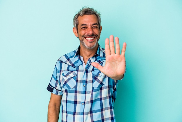 Kaukasischer mann mittleren alters isoliert auf blauem hintergrund, der fröhlich lächelt und die nummer fünf mit den fingern zeigt. Premium Fotos
