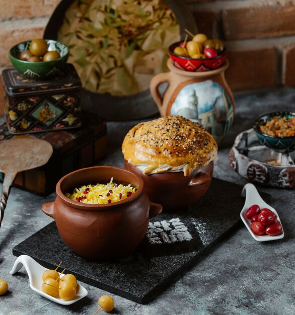 Kaukasischer traditioneller Reis schmücken mit Kräutern innerhalb einer Tonwarenschüssel, die mit Brotbrötchen gedient wird