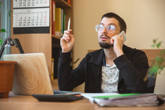 Kostenloses Foto kaukasischer unternehmer, geschäftsmann, manager, der im büro konzentriert arbeitet, erfolgreich