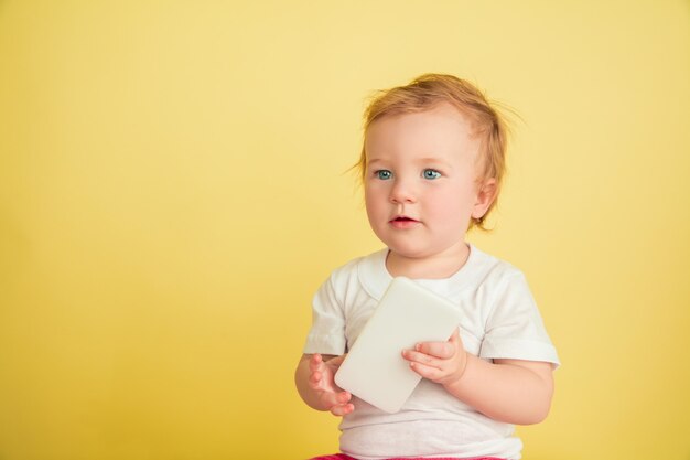 Kaukasisches kleines Mädchen, Kinder lokalisiert auf gelbem Studio