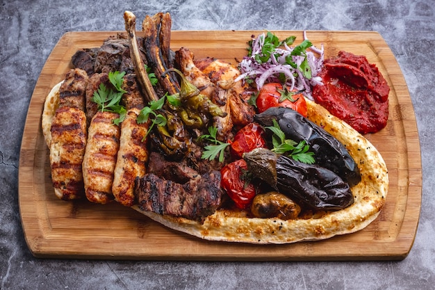 Kebab-Platte mit gegrilltem Gemüse mit Lamm- und Hühnchen-Lula und Tikka-Kebabs mit rotem Zwiebelsalat