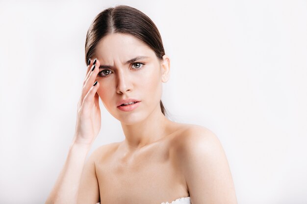 Kein Make-up weibliches Porträt auf isolierter Wand. Frau mit grauen Augen hat Kopfschmerzen.