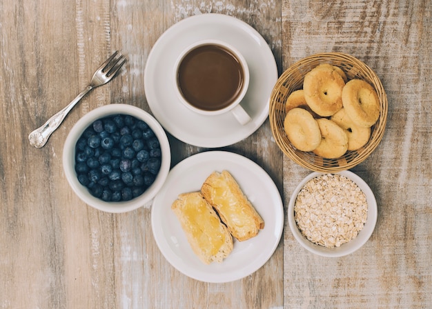 Kekse; Blaubeeren; Hafer; Kekse und Kaffee auf hölzernen Hintergrund