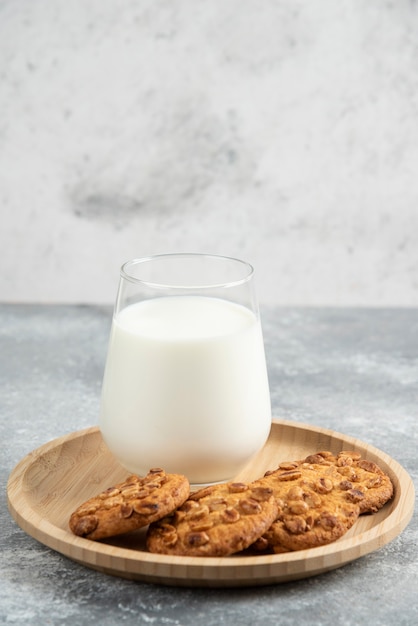 Kekse mit Bio-Erdnüssen und Glas Milch auf Holzplatte.