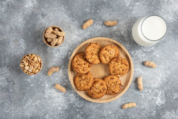 Kekse mit Bio-Erdnüssen und Glas Milch auf Marmortisch.
