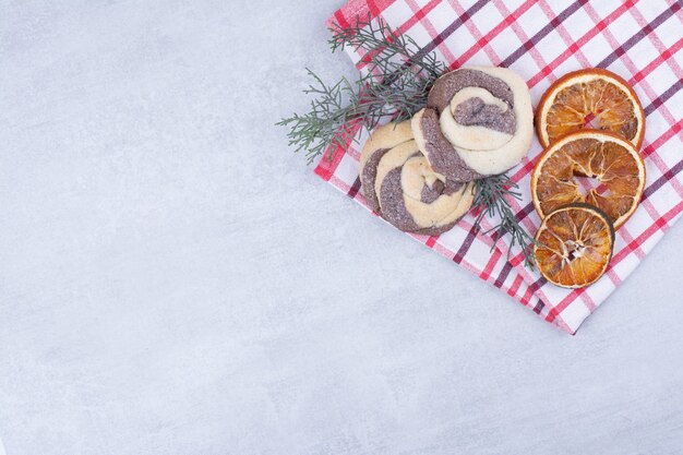 Kekse mit getrockneter Orange auf Tischdecke und Tannenzweig.