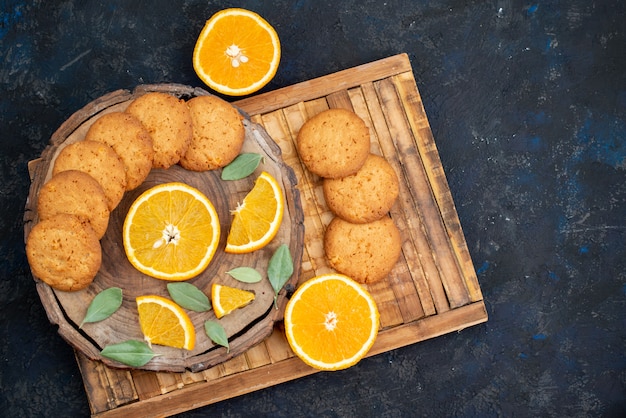 Kostenloses Foto kekse mit orangengeschmack aus der draufsicht mit frischen orangenscheiben auf dem kekszucker des dunklen hintergrundkekses