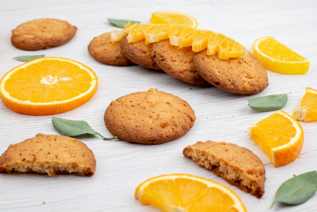 Kekse mit Orangengeschmack aus der Vorderansicht mit frischen Orangenscheiben auf dem leichten Schreibtischfruchtkekskeks