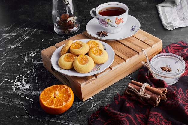 Kekse mit Orangenmarmelade, serviert mit einer Tasse Tee.