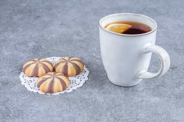Kekse mit Zebramuster und eine Tasse Tee auf Marmoroberfläche